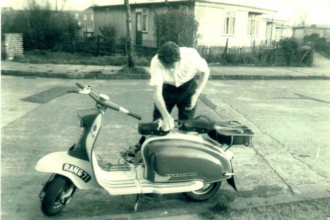 Bob Strudwick working on his scooter, taken from Mr and Mrs Marshalls prefab at No 6, Strattondale Street, Isle of Dogs, London 50s or 60s | Hearn,Jane