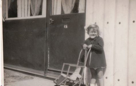 Kathryn with pushchair and doll in front of prefab